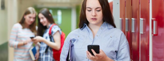 Female High School Student Bullied By Text Message In Corridor Female High School Student Bullied By Text Message In Corridor