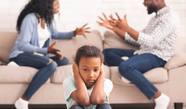 Children and divorce concept. Upset african girl closing ears not to listen parents arguing, sitting on floor at home, feeling lonely.