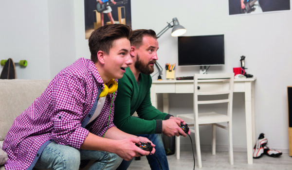 Teen boy playing a computer game with dad