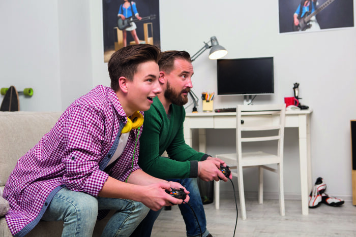 Teen boy playing a computer game with dad