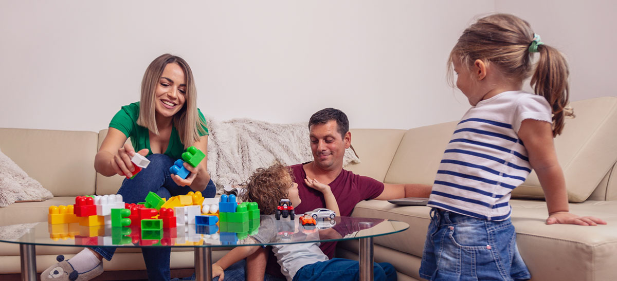 Family time - Young father using a laptop computer for work at home while looking after his son