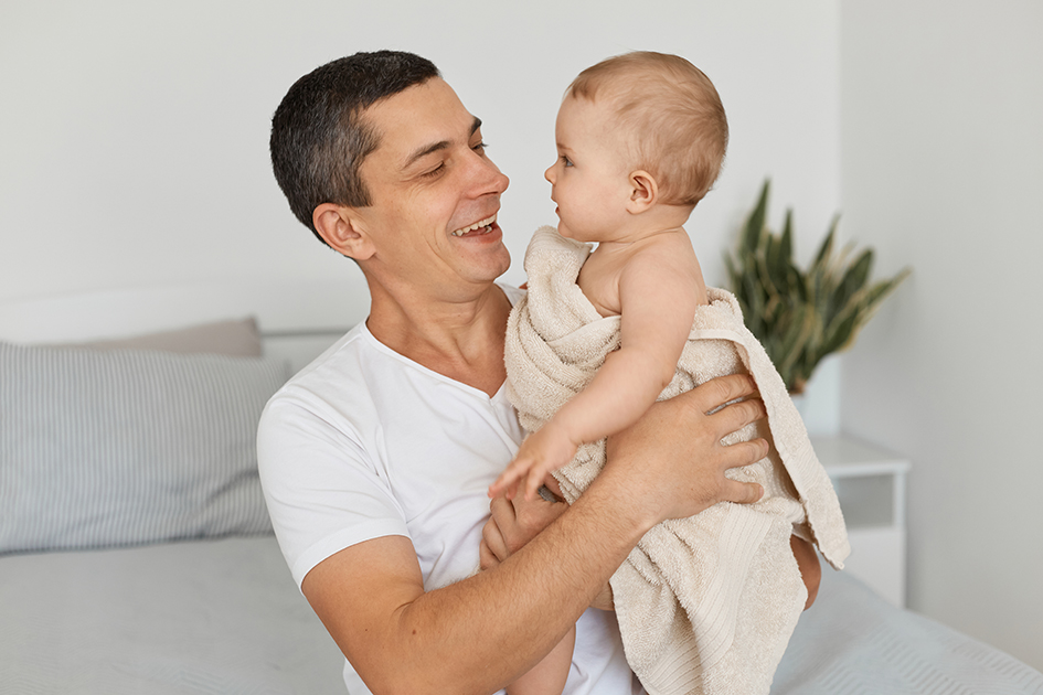 Image of young adult father with his toddler baby girl wrapped in towel