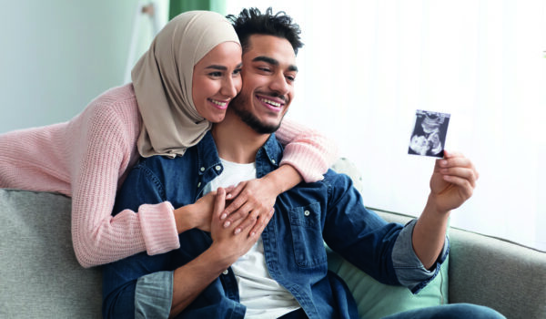 Pregnant Muslim Woman In Hijab And Her Husband Looking At Baby Scan