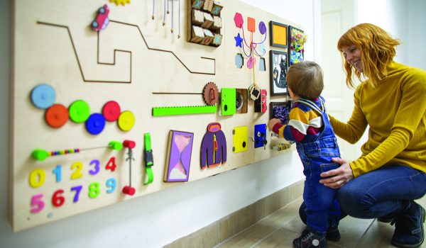 Young mother and her one year old baby son playing with interactive board.