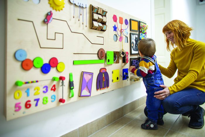 Young mother and her one year old baby son playing with interactive board.