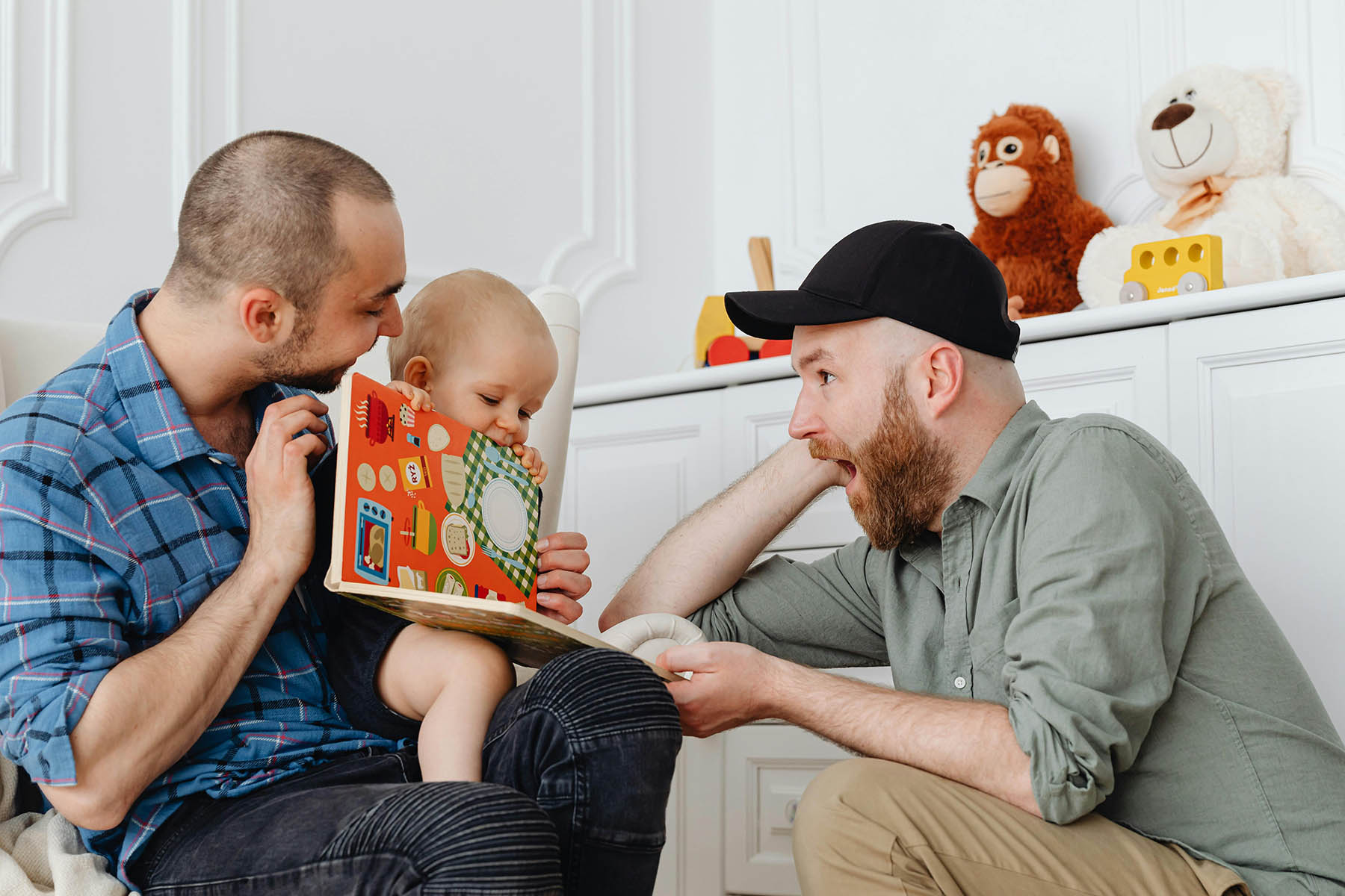 Two men reading a book with a young child